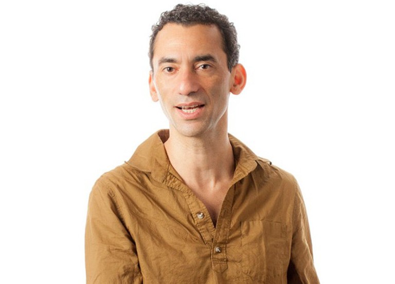 Luis Carlos Sotelo Castro: “A practice that has often gone unnoticed is the art of orchestrating listening situations within restorative transitional justice initiatives.” Man caught in the act of speaking, with short brown hair, and wearing a mustard yellow shirt.